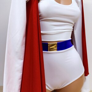 Puede incluir: Traje blanco con una capa roja, un cintur&oacute;n azul con una hebilla dorada y una cadena dorada con botones dorados alrededor del cuello.