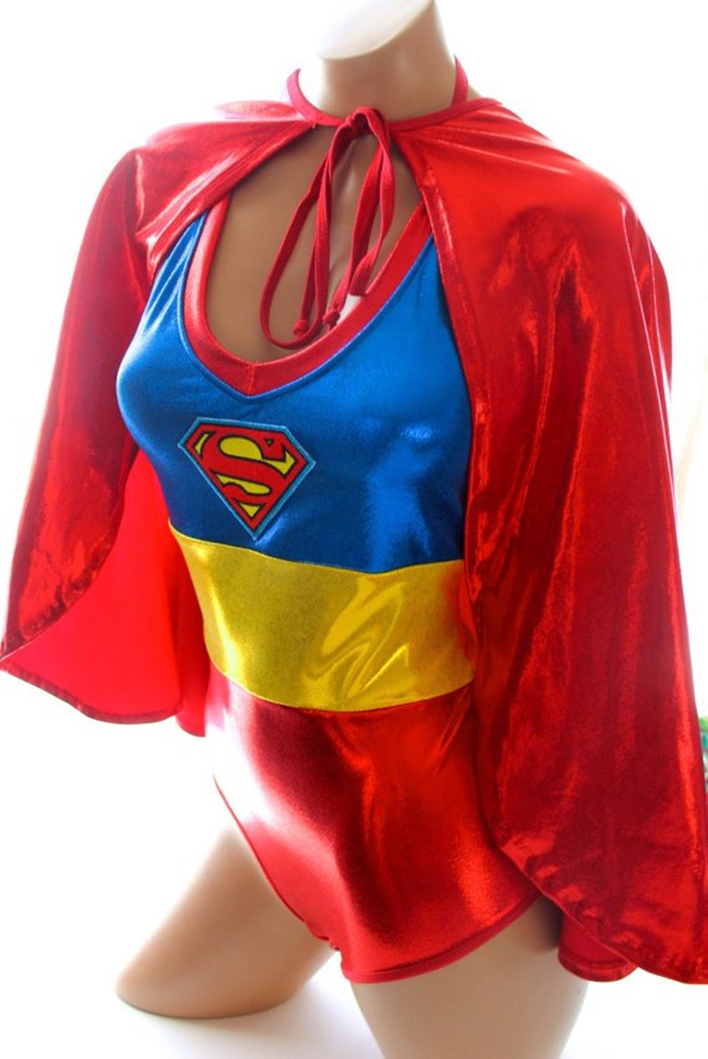 K&ouml;nnte beinhalten: Ein Superman-Kost&uuml;m in Rot, Blau und Gelb. Das Kost&uuml;m besteht aus einem roten Umhang, einem blauen Oberteil mit dem Superman-Logo, einem gelben G&uuml;rtel und einer roten Hose. Das Kost&uuml;m ist aus gl&auml;nzendem, metallischem Stoff gefertigt.