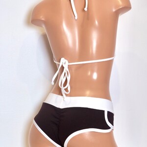May include: Black and white bikini with a halter top and high-waisted bottoms. The bottoms have a white trim and a white stripe down the side.