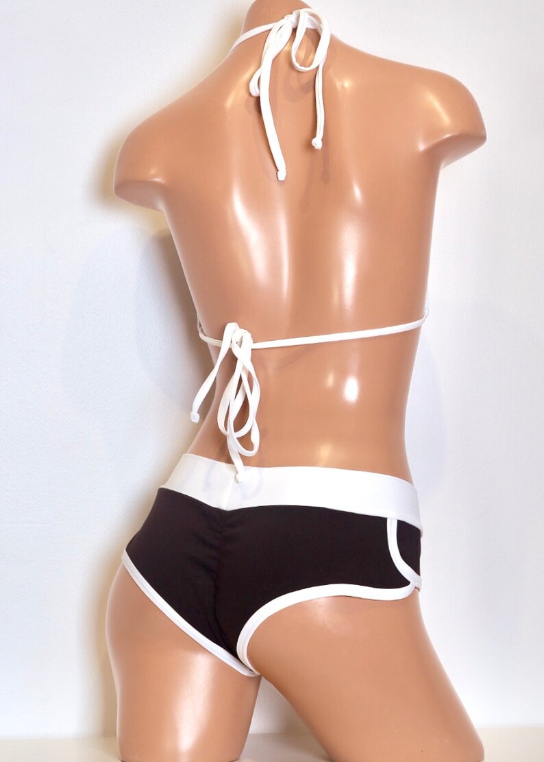 May include: Black and white bikini with a halter top and high-waisted bottoms. The bottoms have a white trim and a white stripe down the side.