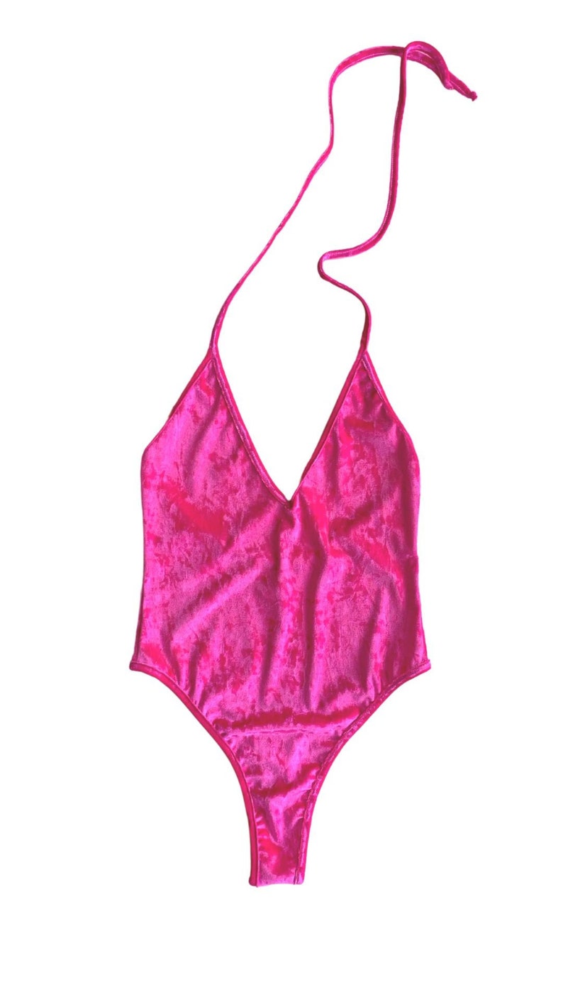 May include: A bright pink velvet one-piece swimsuit with a halter neck strap.