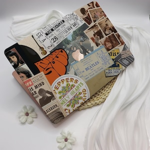Puede incluir: Un objeto decorativo en forma de diamante con un collage de recuerdos de los Beatles. Presenta entradas de conciertos, fotografías y el logotipo de Apple Records. La paleta de colores incluye beige, marrón y naranja, con acentos blancos y negros.