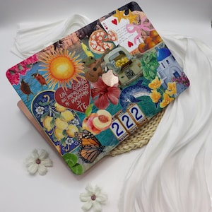 May include: A laptop skin with a colorful collage design featuring a sun, a heart with Italian text, a butterfly, a peach, a lemon tree, a pizza, a guitar, a dolphin, and the number 222.