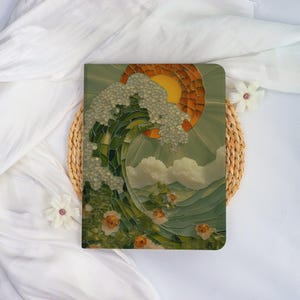 May include: A decorative journal with a mosaic-style design featuring a stylized wave, sun, and flowers. The cover has a green, orange, and white colour scheme. The journal is placed on a woven mat and white fabric.
