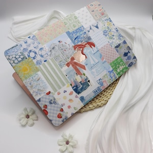 May include: A laptop computer with a colorful patchwork design featuring sailboats, a lobster, and strawberries. The design is reminiscent of a quilt or patchwork fabric.