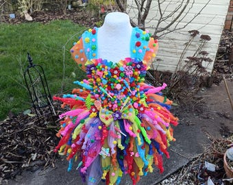 Könnte beinhalten: Ein farbenfrohes Tütükleid, verziert mit Süßigkeiten, Lutschern und anderen süßen Leckereien. Das Kleid ist aus Tüll und hat einen Regenbogen an Farben.