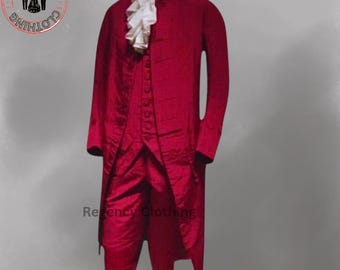 May include: A red, long-sleeved coat with a white ruffled collar and matching red breeches. The coat has a high collar and a long, flowing skirt. The breeches are knee-length and have a button closure at the front. The outfit is a traditional style of clothing worn in the 18th century.