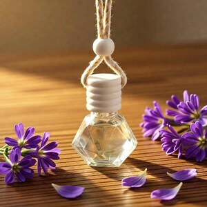 May include: A small, clear, geometric glass bottle filled with liquid, featuring a ribbed white wooden cap and a thick beige rope for hanging. The bottle is surrounded by several vibrant purple flowers and loose petals on a flat surface.