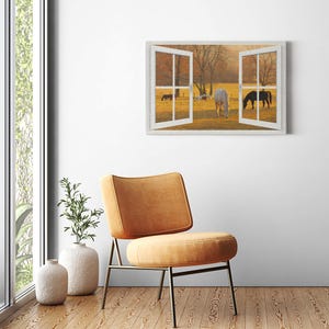 Puede incluir: Una ventana con marco blanco con vista a un campo con caballos pastando en la luz dorada de la puesta de sol. La ventana está abierta y los caballos están en la distancia.