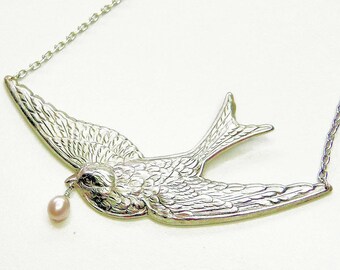 Uccello che tiene rosa perla collana