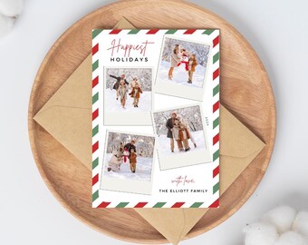 May include: A holiday card with family photos, the words "Happiest Holidays" in red script, and a red and green striped border. The card is on a wooden tray with a brown envelope.