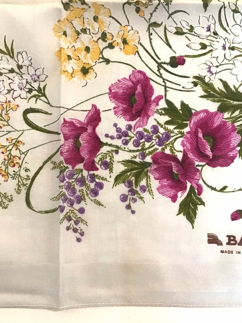 Pu&ograve; includere: Fazzoletto di cotone bianco con un motivo floreale con papaveri rosa, fiori gialli e foglie verdi. Il fazzoletto ha un'etichetta marrone che recita "Made in"
