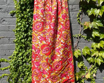 May include: A long, flowing skirt with a vibrant floral pattern in shades of red, pink, yellow, and white. The skirt has a paisley-inspired design and a gathered waistband.