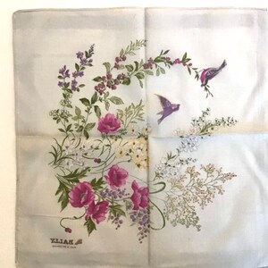 Pu&ograve; includere: Un foulard di seta blu chiaro con un motivo floreale che presenta papaveri rosa, foglie verdi e fiori bianchi. Due piccoli uccelli volano nell'angolo in alto a destra del foulard. Il testo "BAILLY" &egrave; stampato nell'angolo in basso a sinistra del foulard.