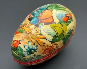 May include: A vintage Easter egg-shaped container with a colourful illustration of a chicken and other farm animals. The egg is made of papier-mâché and has a red trim around the edge.