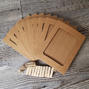 May include: A set of ten brown cardboard picture frames with a rounded opening for a photo. The frames are arranged in a fan shape and come with a string of wooden clothespins.
