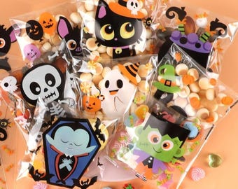 May include: Clear cellophane bags filled with Halloween-themed candies and treats. Each bag features a different cartoon character, including a black cat, ghost, and Frankenstein's monster. The bags are decorated with bats, pumpkins, and other festive elements.
