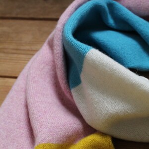 Peut inclure: Une &eacute;charpe en tricot ray&eacute;e rose, blanche, bleue et jaune.