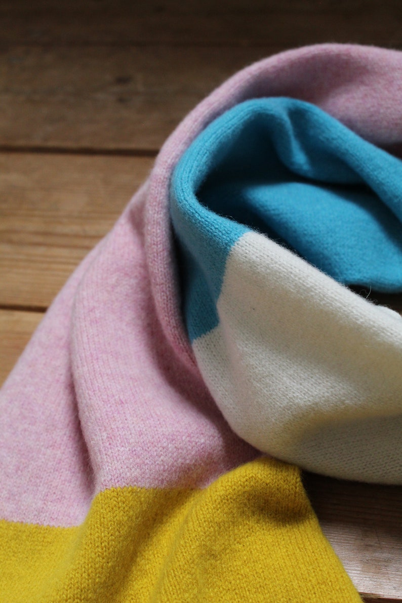 Peut inclure: Une &eacute;charpe en tricot ray&eacute;e rose, blanche, bleue et jaune.