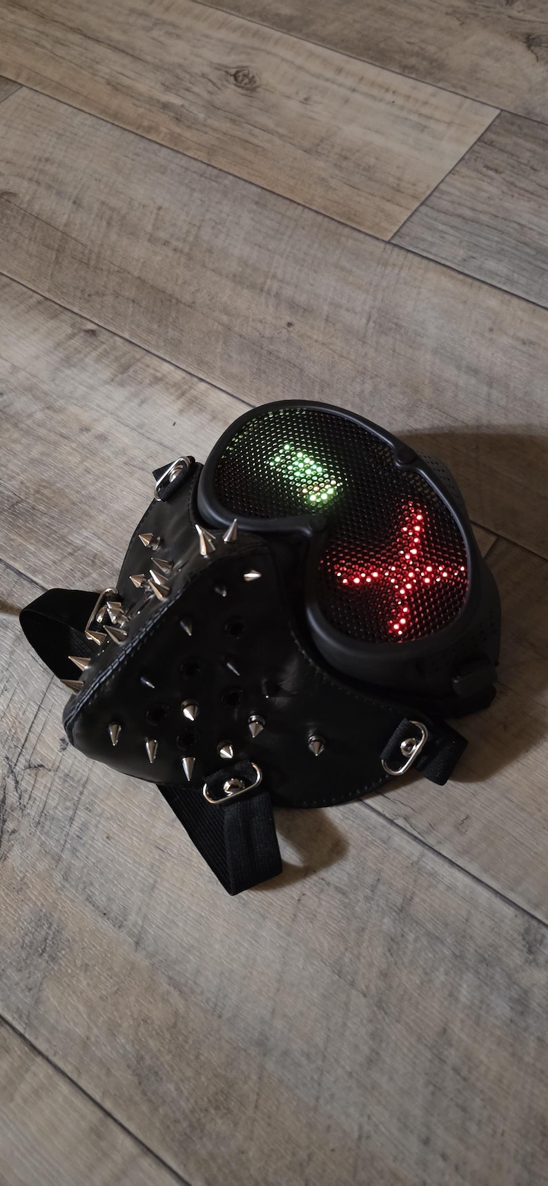 Pode incluir: M&aacute;scara de couro preta com pontas prateadas e luzes LED. A m&aacute;scara tem um design futurista com uma exibi&ccedil;&atilde;o de luz em forma de cruz em luzes vermelhas e verdes. A m&aacute;scara &eacute; projetada para cosplay ou fantasia.
