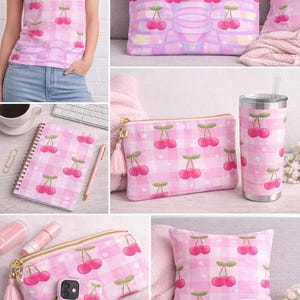 May include: A collection of pink gingham patterned items featuring a cherry design. Includes a t-shirt, tote bag, notebook, cosmetic bag, tumbler, phone case, pillow, and mug. The items have a repeating pattern of cherries.