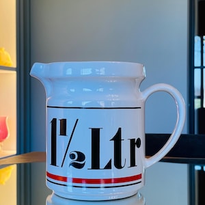 May include: White ceramic jug with a black and red stripe design. The jug has a handle and says "1 1/2 Ltr" on the front.