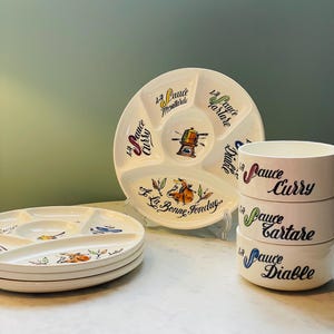 May include: A set of white ceramic plates and bowls featuring colorful illustrations and French text. The plates are divided into sections with labels like La Sauce Moutarde, La Sauce Tartare, La Sauce Curry, and La Sauce Diable, plus a central fondue pot graphic.