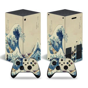 Puede incluir: Un conjunto de dos skins personalizados para la consola Xbox Series X y el mando, con un estampado japonés en madera de una gran ola rompiendo contra una costa rocosa. El diseño está en tonos azules, blancos y grises sobre un fondo beige.