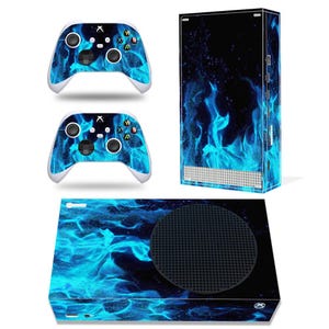 May include: A gaming console and two controllers with a blue flame design. The console is black with a circular vent and the controllers have white accents. The flame design covers the console and controllers.