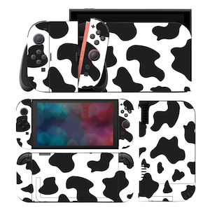 Op de afbeelding: Een set skins met koeienprint in zwart en wit voor een Nintendo Switch-console. De skins bedekken de console, Joy-Cons en dock en bieden een unieke uitstraling. Het ontwerp toont grote, onregelmatige zwarte vlekken op een witte achtergrond.