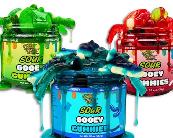 May include: Three jars of Sour Gooey Gummies in green apple, blue raspberry, and wild cherry flavors. Each jar is overflowing with colorful gummy candies, with the green and blue varieties dripping down the sides. Each jar is 20 oz.
