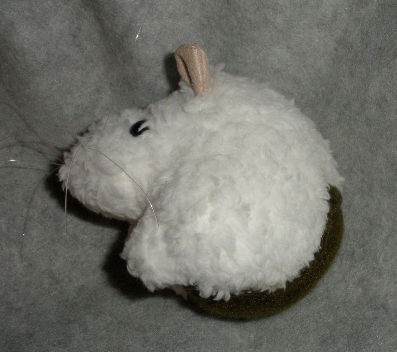 Op de afbeelding: Witte pluche muis met een bruine vilt bodem. De muis heeft een klein, zwart oog en een lange, dunne staart.