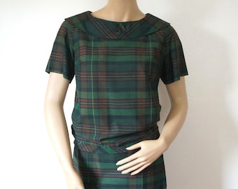 May include: A green and brown plaid dress with a Peter Pan collar and short sleeves.