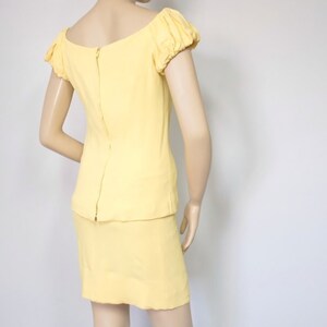 May include: A yellow dress with a fitted bodice and a skirt. The dress has a scoop neckline and short, puffed sleeves.