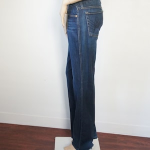 Könnte beinhalten: Eine dunkelblaue Jeans mit weitem Bein. Die Jeans hat einen klassischen Fünf-Taschen-Stil und einen leicht ausgefransten Saum.