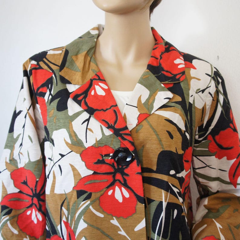 Puede incluir: Blazer con estampado floral con un patr&oacute;n audaz de rojo, verde, marr&oacute;n y blanco. La chaqueta tiene un solo bot&oacute;n negro y solapas cl&aacute;sicas. La tela parece ligera, adecuada para climas c&aacute;lidos. La longitud del blazer es de unos 70 cm.