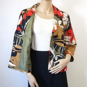 Puede incluir: Blazer con estampado floral con detalles en rojo, negro, blanco y marr&oacute;n. El blazer tiene un cierre de un solo bot&oacute;n negro y un forro verde. Las mangas son de tres cuartos.