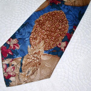 May include: A blue silk tie with a peacock design. The peacock is brown and gold with a blue background. The tie has a floral pattern with red and white flowers.