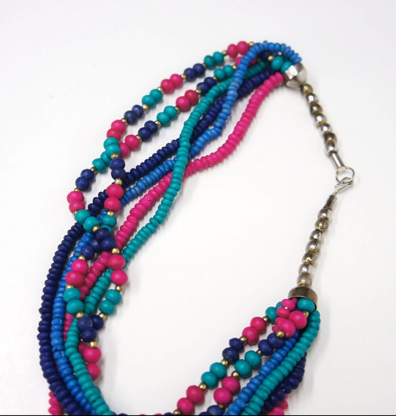 May include: Multi-strand necklace with pink, blue, and turquoise beads. The necklace has a silver clasp.