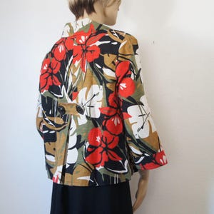Puede incluir: Chaqueta de manga corta con un vibrante estampado floral. La chaqueta presenta grandes flores rojas, hojas blancas y acentos de negro, verde y marr&oacute;n. Tiene cierre de bot&oacute;n y un corte entallado, adecuado para un look elegante.
