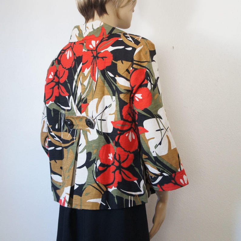 Puede incluir: Chaqueta de manga corta con un vibrante estampado floral. La chaqueta presenta grandes flores rojas, hojas blancas y acentos de negro, verde y marr&oacute;n. Tiene cierre de bot&oacute;n y un corte entallado, adecuado para un look elegante.