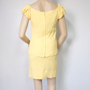 May include: A yellow dress with a fitted skirt and a short-sleeved top with puffed sleeves. The dress has a scoop neckline and a zipper closure in the back.