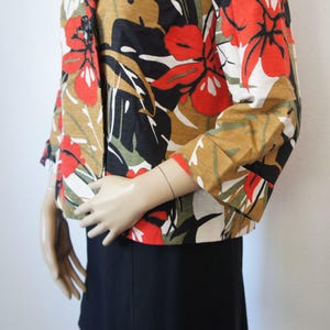 Puede incluir: Chaqueta de manga corta con un llamativo estampado floral. Los colores incluyen rojo, blanco, negro, verde y marr&oacute;n. Las mangas son de tres cuartos. La chaqueta parece estar hecha de una tela ligera, ideal para climas c&aacute;lidos.