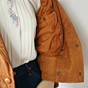 K&ouml;nnte beinhalten: Eine braune Lederjacke mit Rei&szlig;verschluss und einer Innentasche. Die Jacke hat eine strukturierte Oberfl&auml;che und ist ungef&uuml;ttert.