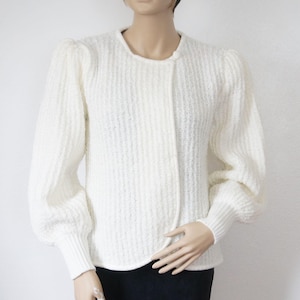 May include: White knitted cardigan with a single button closure and puffed sleeves.