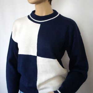 May include: A navy blue and white checkered sweater with a white ribbed collar and cuffs.