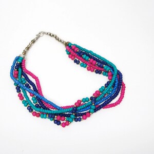 May include: Multi-strand necklace made of small, colorful beads. The necklace features turquoise, pink, and blue beads.