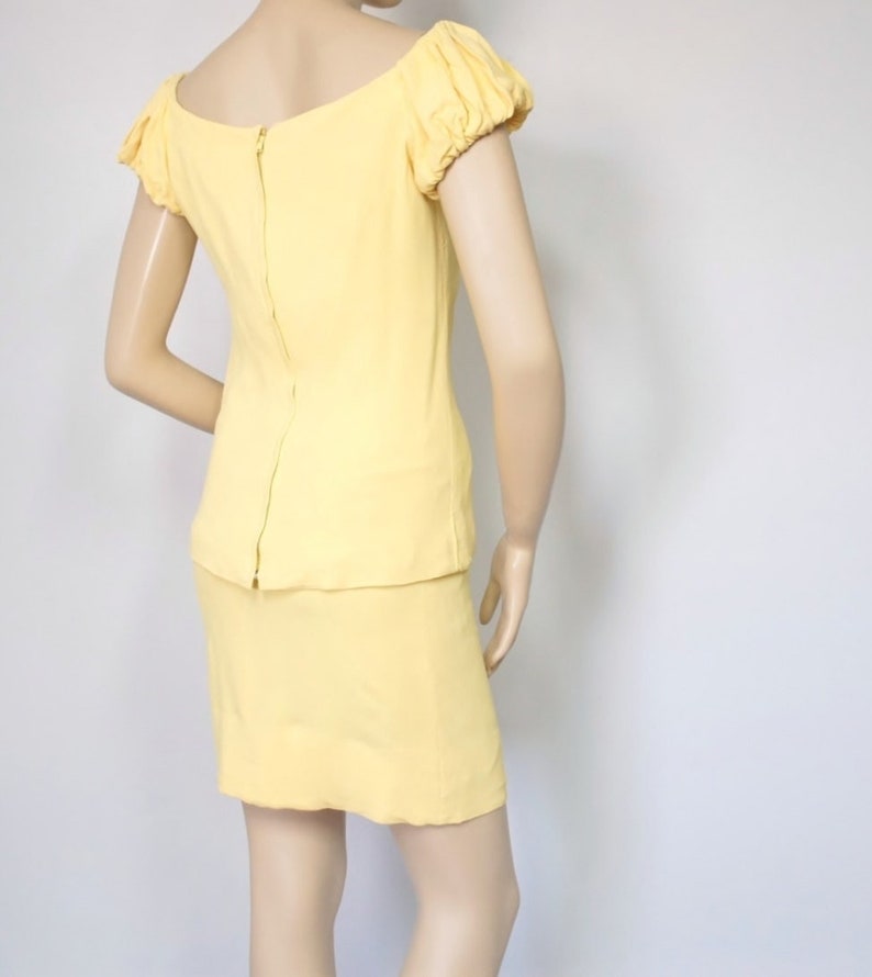 May include: A yellow dress with a fitted bodice and a skirt. The dress has a scoop neckline and short, puffed sleeves.