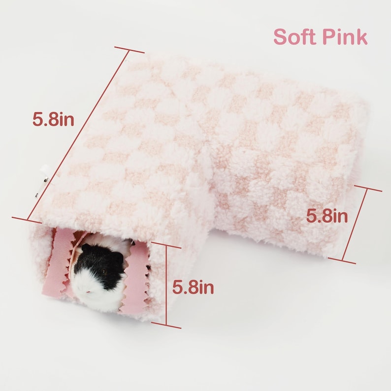 May include: A soft pink, L-shaped pet bed with a checkered pattern. The bed measures 5.8 inches on each side and features a small pet inside. The text "Soft Pink" is visible in the image.
