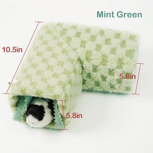May include: A mint green pet tunnel, 10.5 inches long and 5.8 inches wide, with a checkered pattern. The tunnel is made of soft, plush material. A small pet with black and white fur is inside the tunnel. The text "Mint Green" is visible.